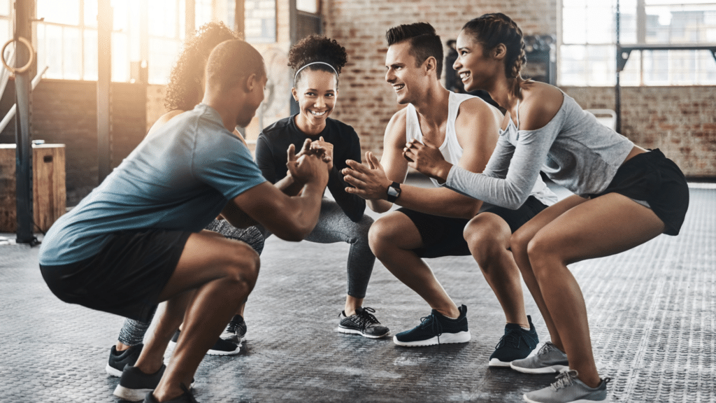 Groupe de sportifs faisant des squats ensemble en salle de sport - Le 20/80 Fit Club Haute Savoie