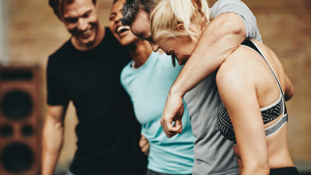 Groupe de sportifs hilares se tenant par les épaules après un cours collectif au 20/80 Fit Club de Sallanches