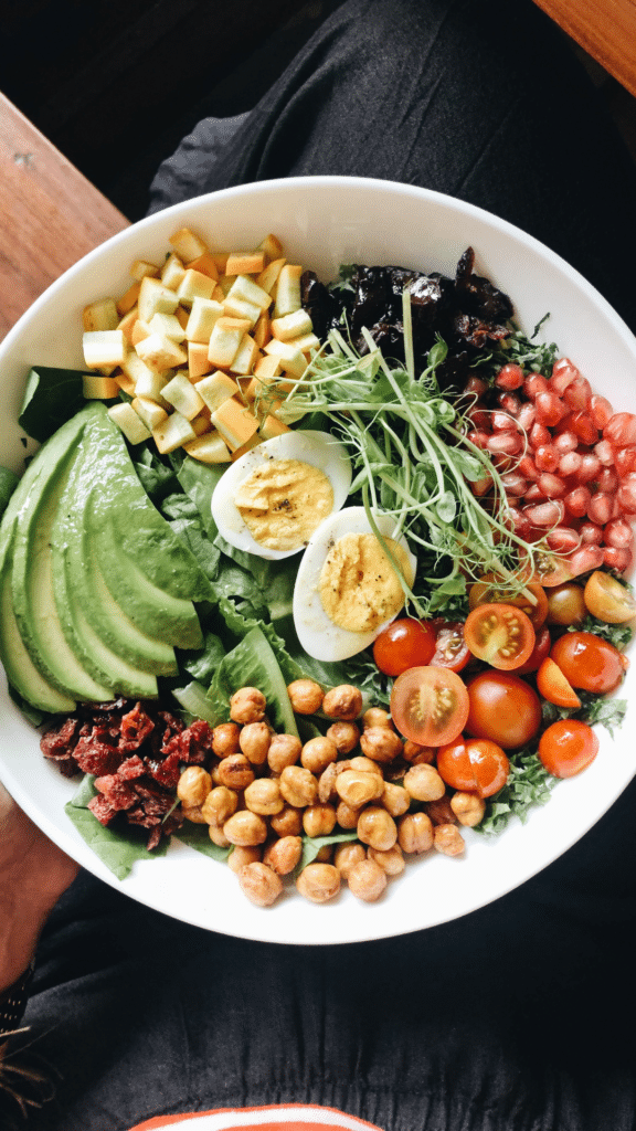 Bowl coloré composé d’avocat, œufs, légumes frais, pois chiches et graines