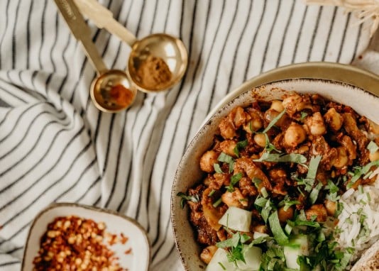 Bol de chili végétarien aux haricots rouges, pois chiches et tomates concassées garni de coriandre fraîche et avocat lors d'un atelier cuisine